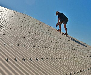 FLAT ROOFS A man working on a metal roof.